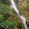 Hiker jumping across a waterfall, wearing Columbia