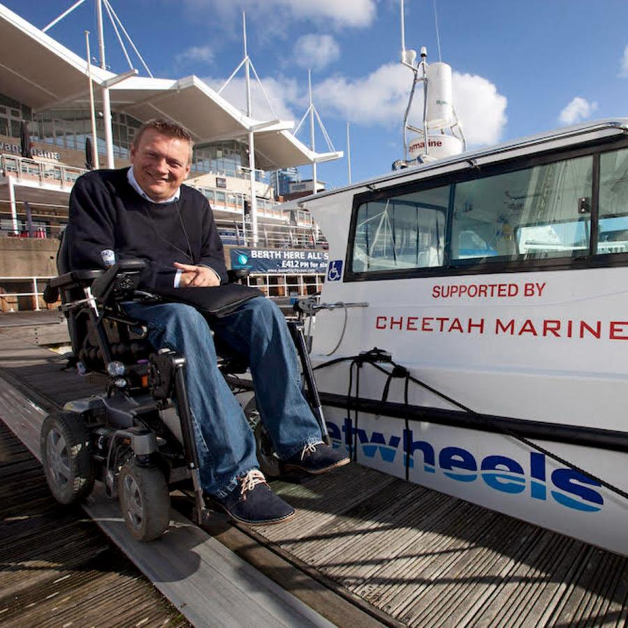 Man in wheelchair next to catamaran