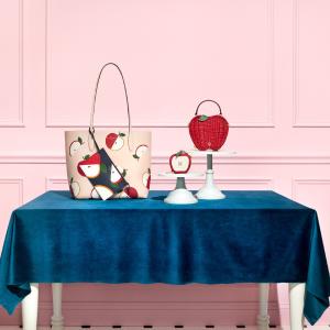 Novelty handbags on a velvet-covered table against a pink panelled wall 