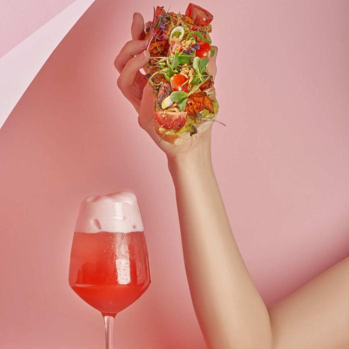 Glass of pink fizz and a hand holding a breakfast taco